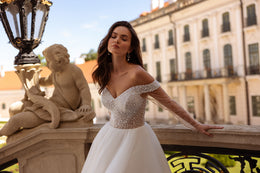 Pearl-beaded off-shoulder neckline and fitted bodice on an ivory ball gown wedding dress