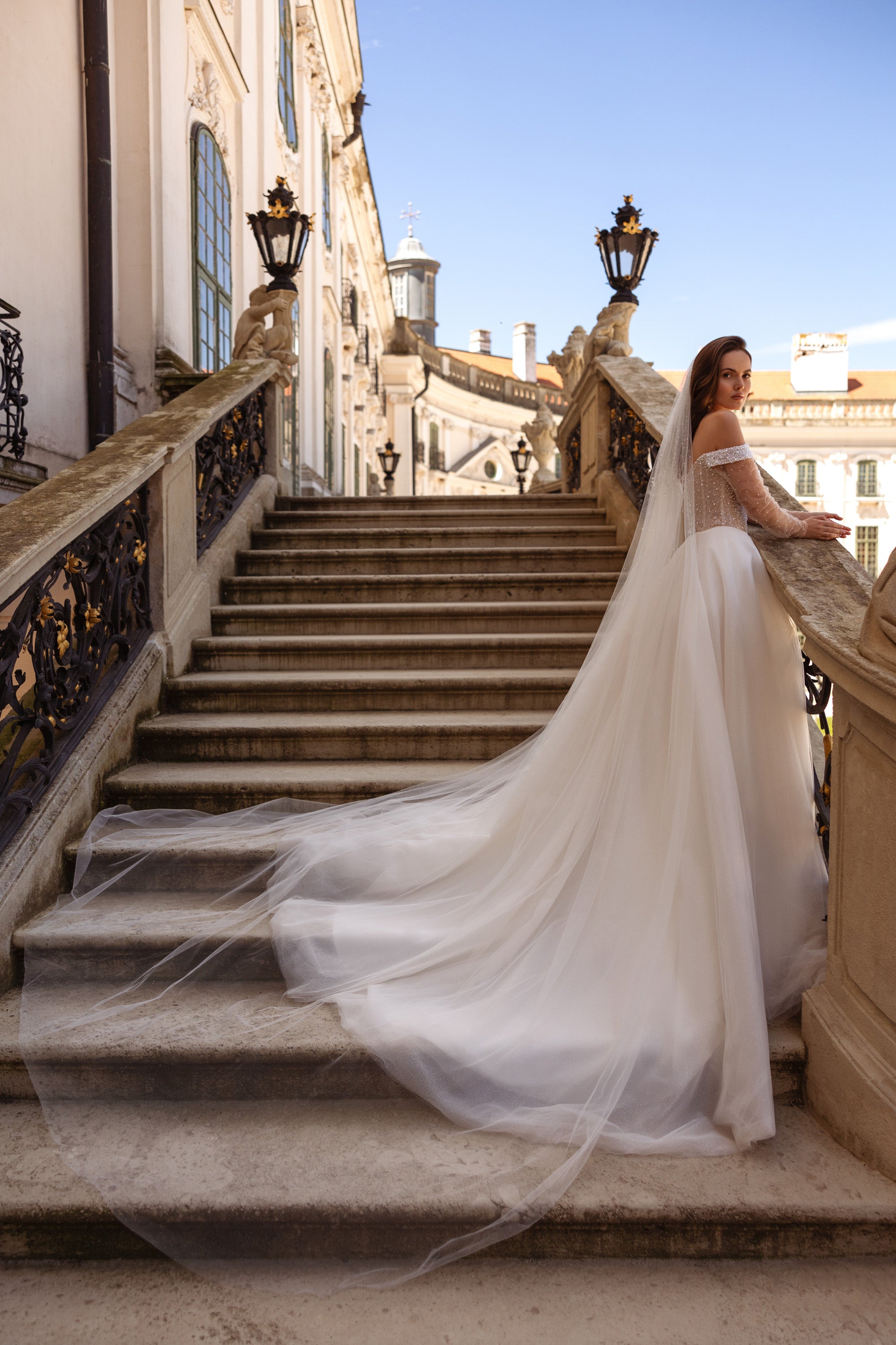 Long sweeping train and full skirt on an ivory wedding dress with an off-shoulder beaded bodice