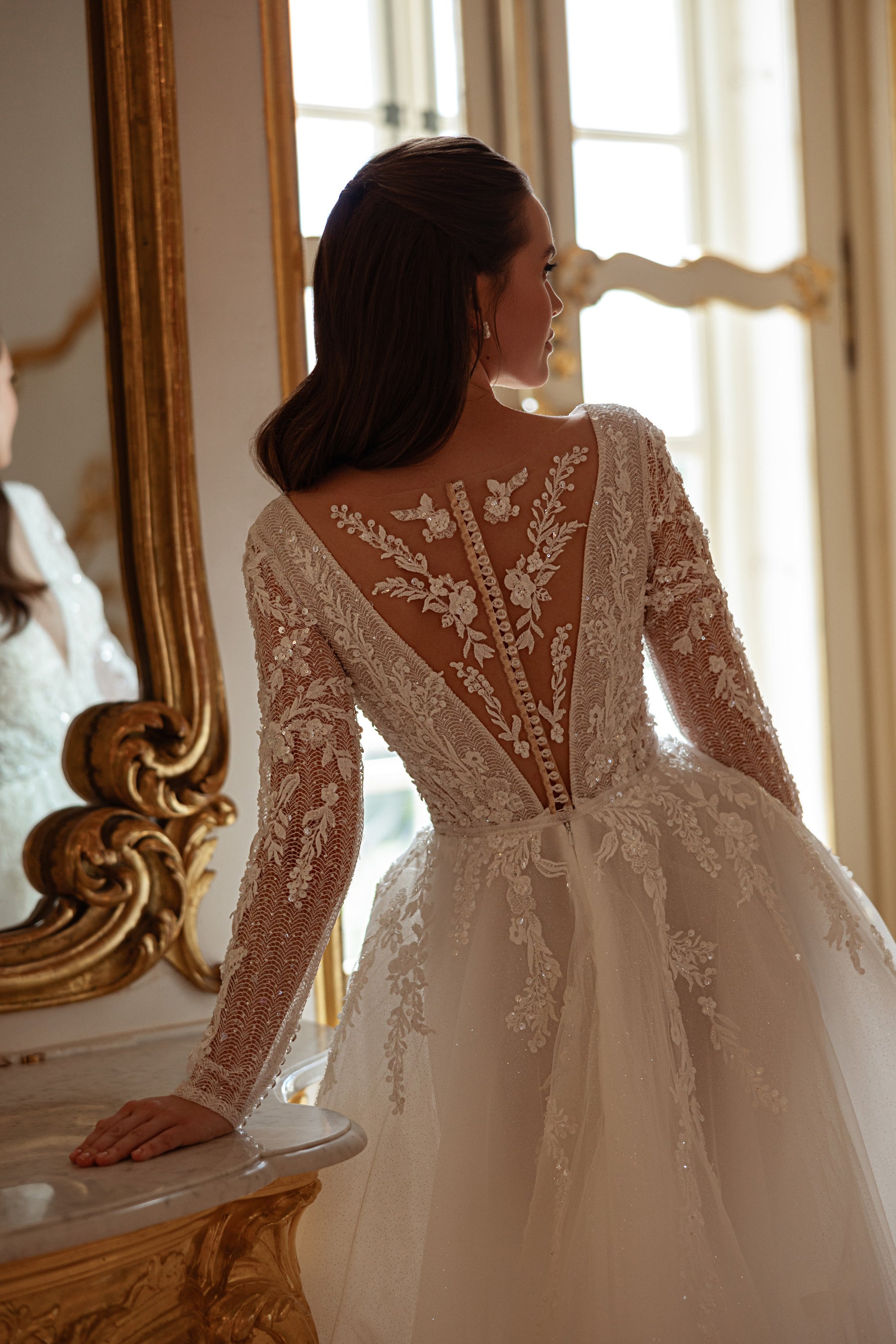 Ivory wedding dress with a deep illusion lace back, floral long sleeves, covered buttons, and a full A-line skirt