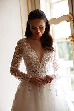 Ivory wedding dress featuring a plunging V-neckline, long floral lace sleeves, a beaded waist, and a full skirt