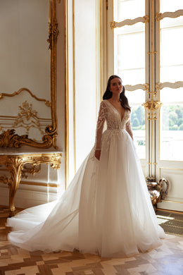 Full-length ivory wedding dress with a V-neck lace bodice, long sleeves, and a flowing A-line train