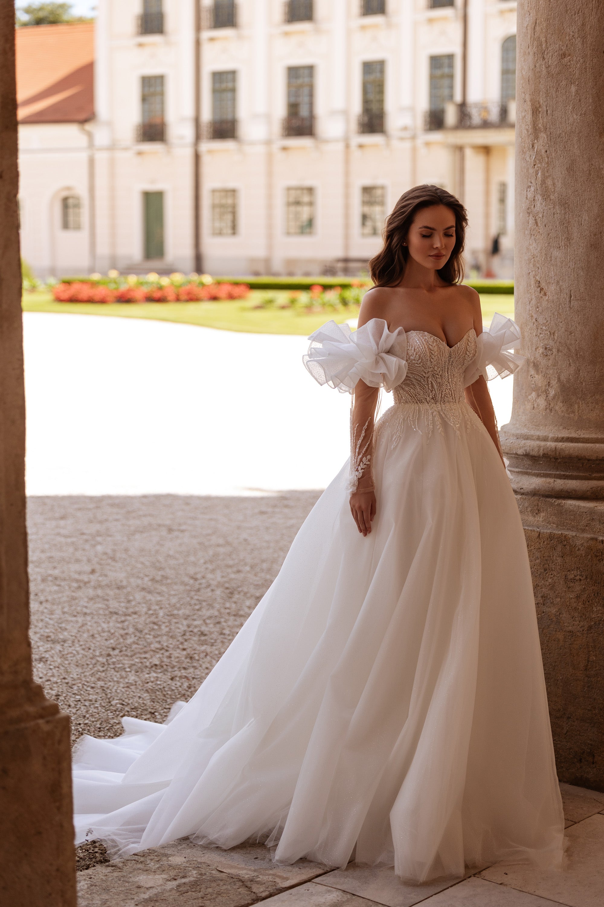 Ivory A-line wedding dress with a beaded sweetheart bodice, off-shoulder puff sleeves, and sweeping train