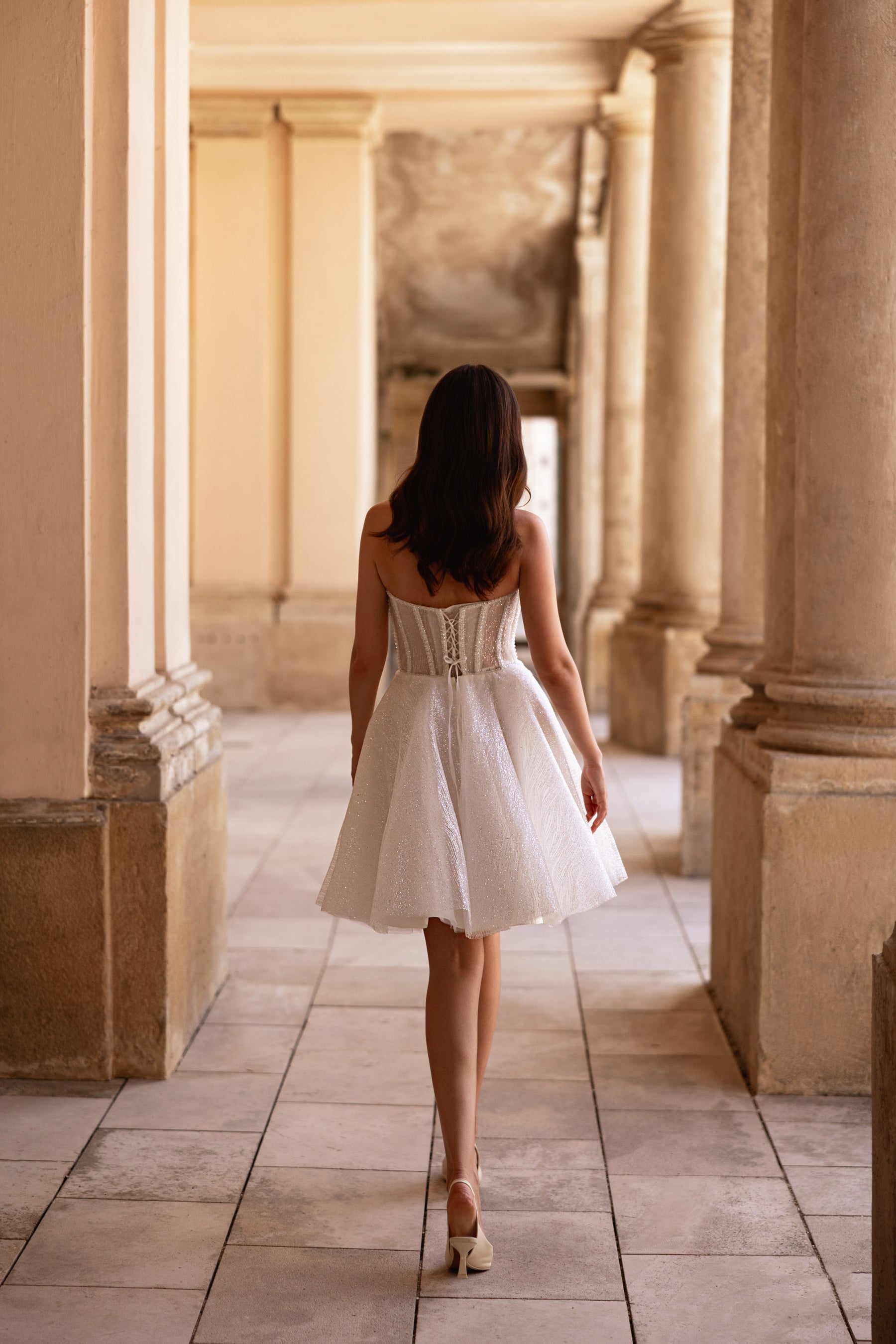 Back of an ivory wedding dress showing a structured corset bodice and short A-line skirt