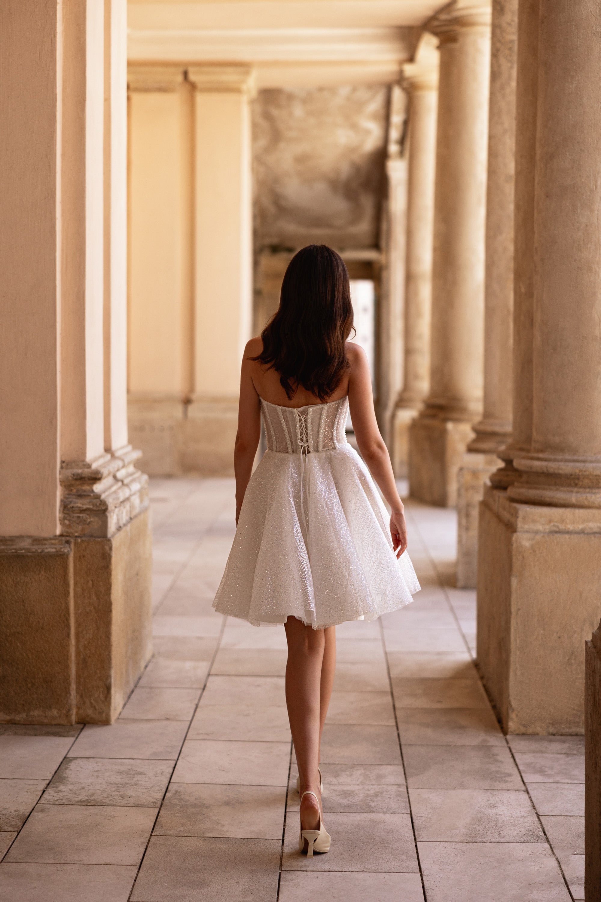 Back of an ivory wedding dress showing a structured corset bodice and short A-line skirt