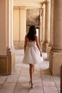 Back of an ivory wedding dress showing a structured corset bodice and short A-line skirt
