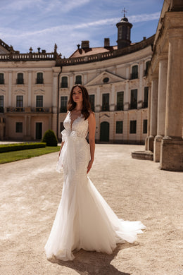 Ivory mermaid wedding dress with a deep V-neckline, beaded lace bodice, and flowing tulle train