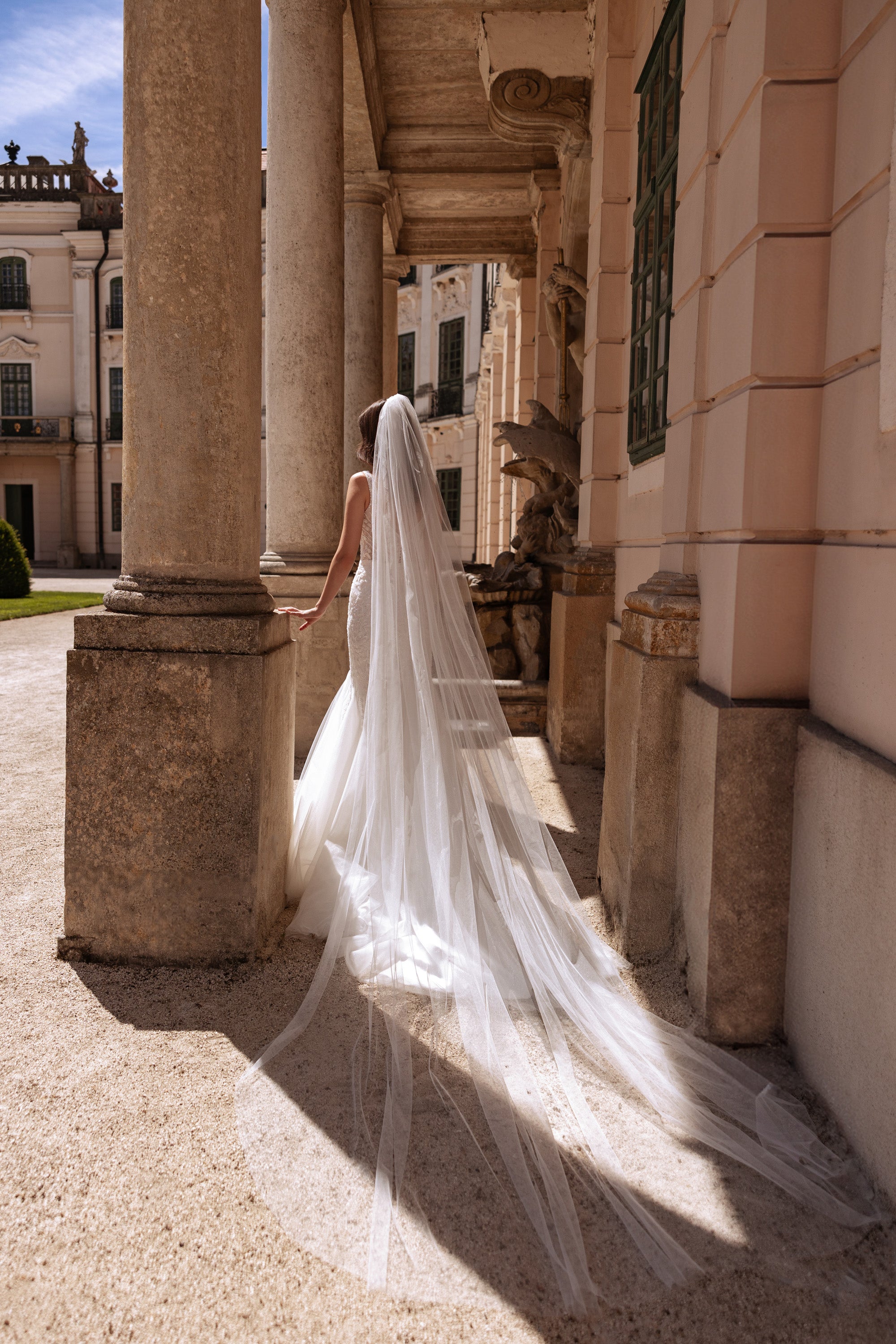 Ivory mermaid wedding dress with a fitted silhouette and long, sweeping tulle train seen from behind