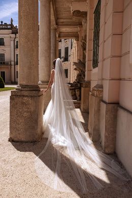 Ivory mermaid wedding dress with a fitted silhouette and long, sweeping tulle train seen from behind