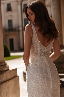 Low V-back wedding dress with covered buttons, thin straps, and intricate beaded lace throughout