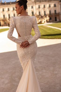 Lace-backed ivory wedding dress with long sleeves, covered buttons, and a flared train