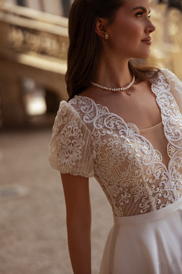 Ivory wedding dress with floral lace bodice, short puff sleeves, scoop neckline, and satin waistband