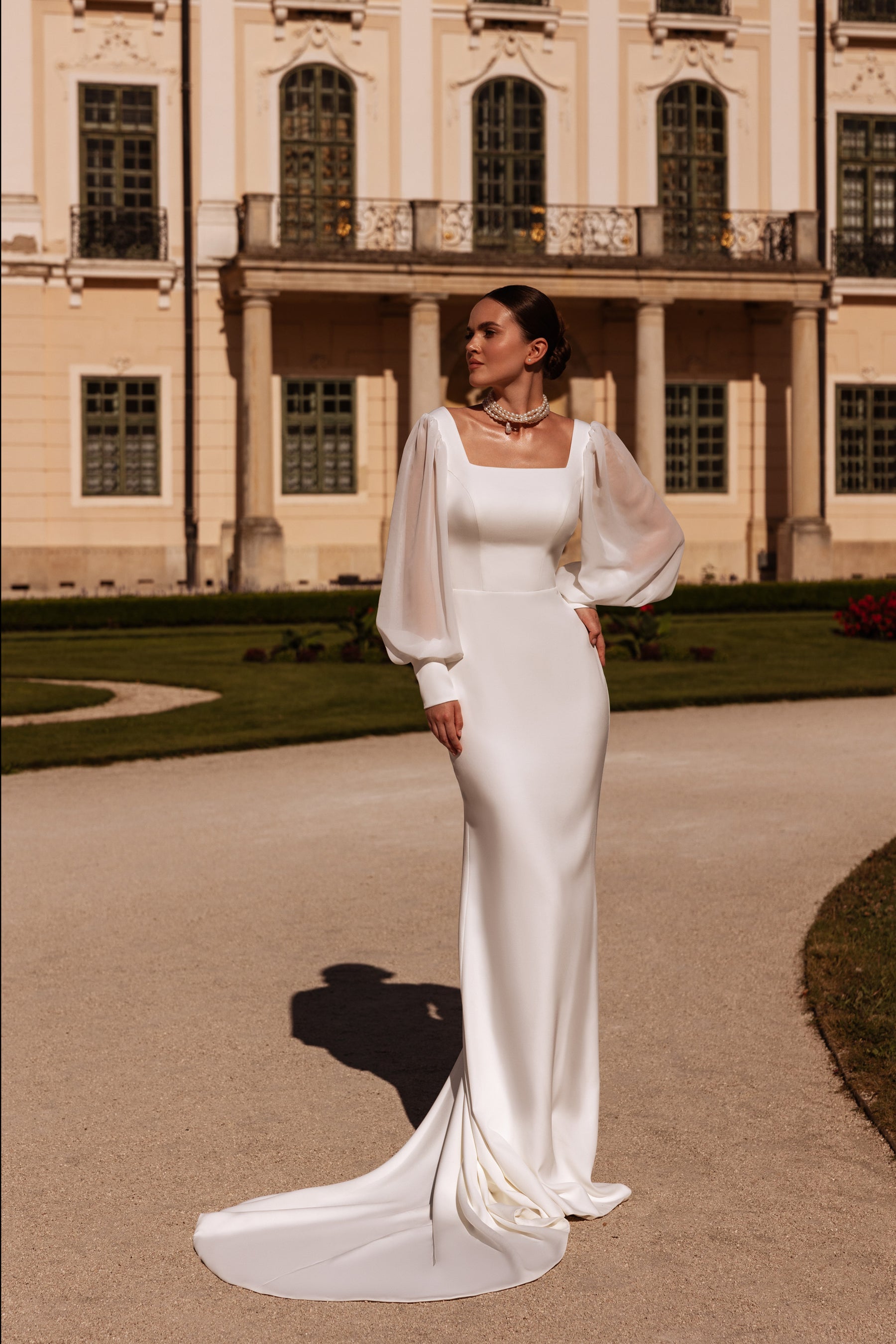 Fitted ivory sheath wedding dress with bishop sleeves, square neckline, and a long pooled train