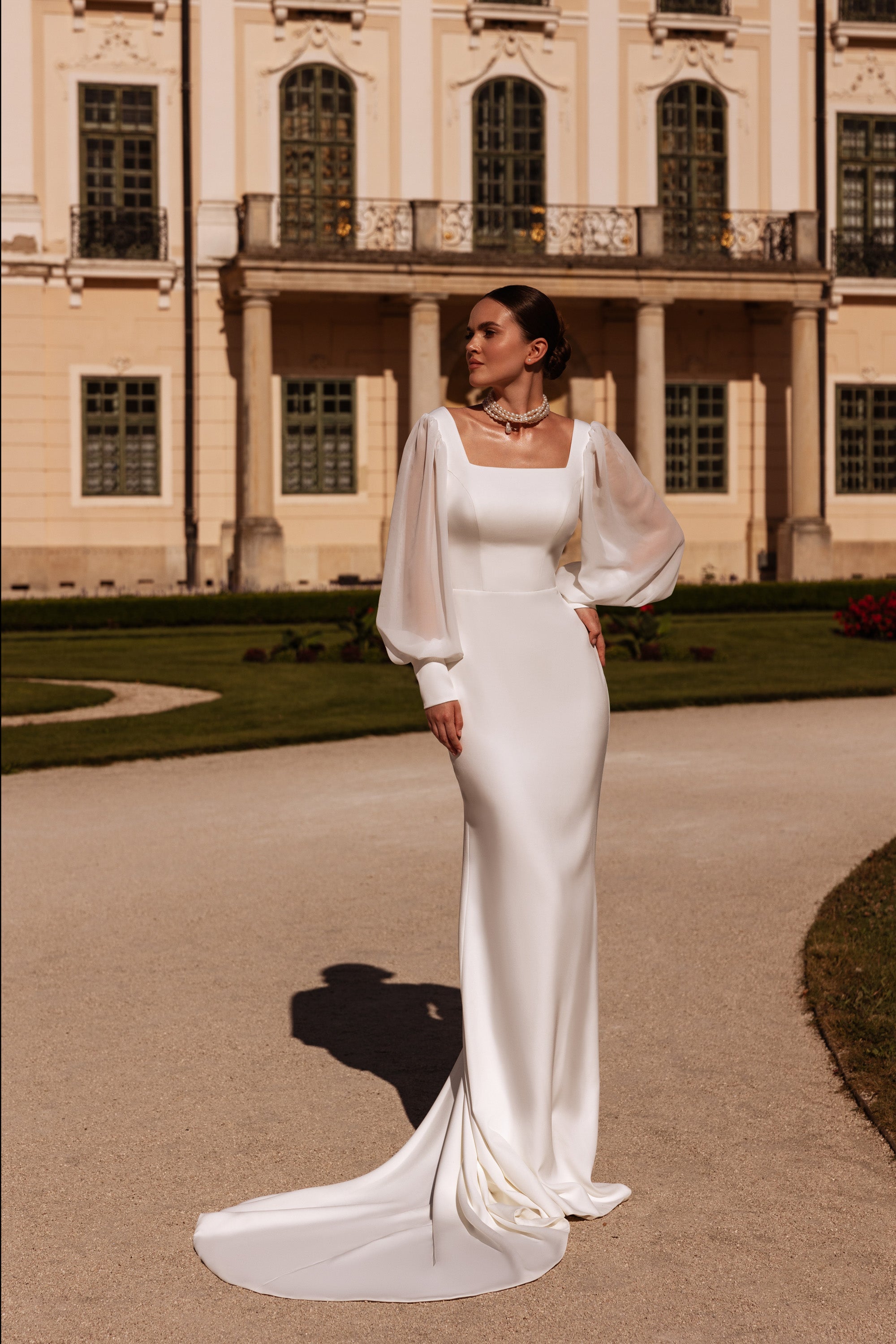 Fitted ivory sheath wedding dress with bishop sleeves, square neckline, and a long pooled train