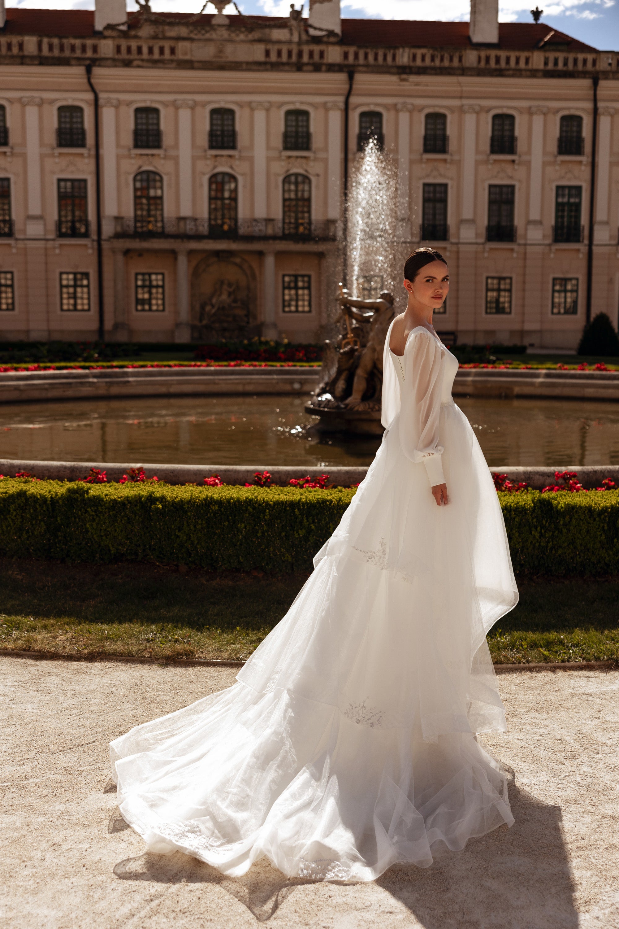 Side view of an ivory wedding dress with flowing bishop sleeves, fitted bodice, and long train