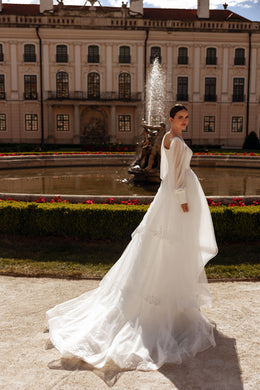 Side view of an ivory wedding dress with flowing bishop sleeves, fitted bodice, and long train