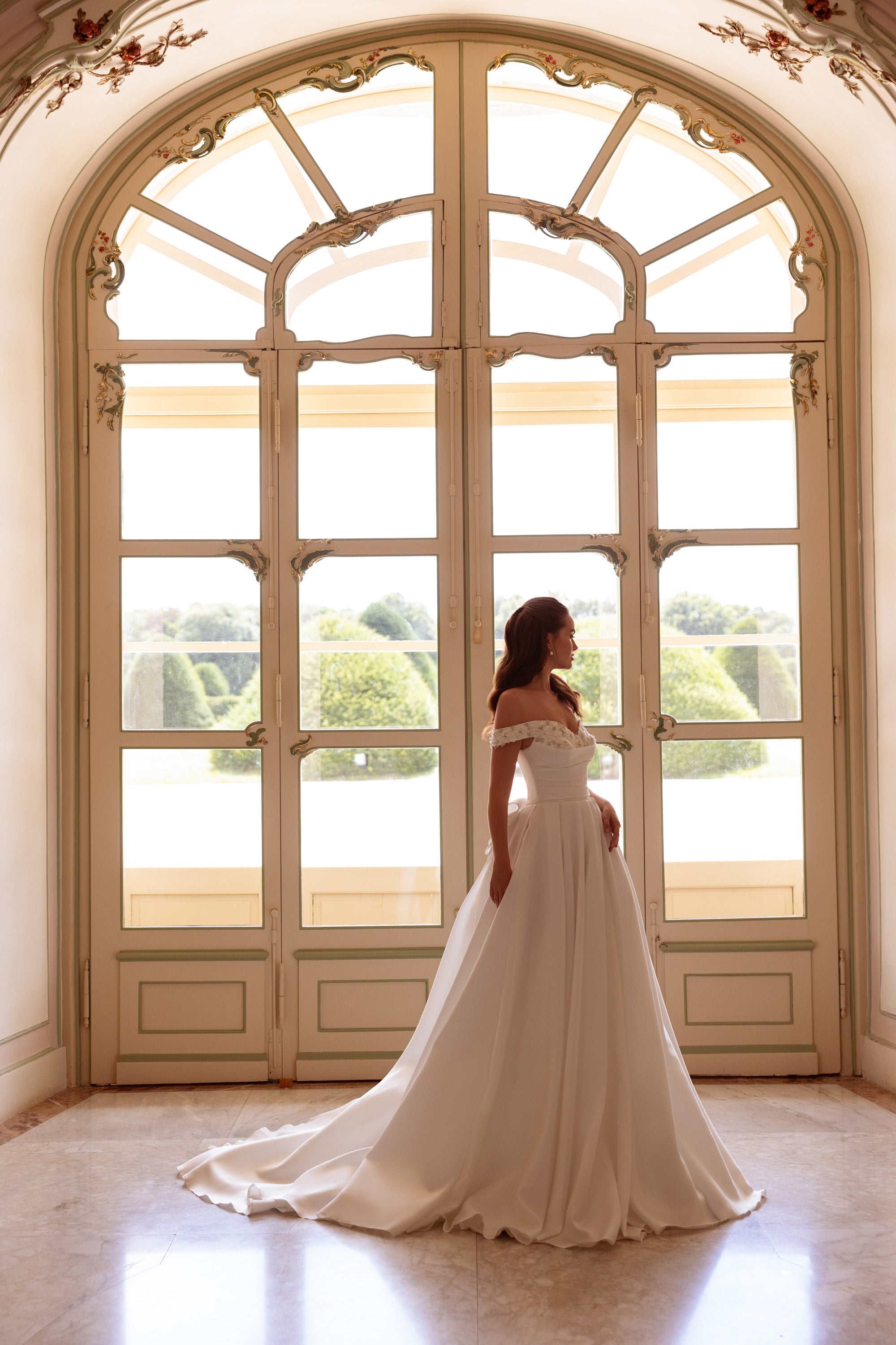 Ivory A-line wedding dress with an off-the-shoulder bodice and sweeping floor-length train