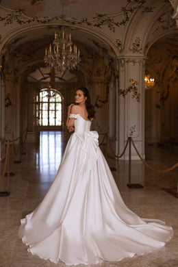 Ivory wedding dress with an off-the-shoulder bodice, oversized back bow, and sweeping train