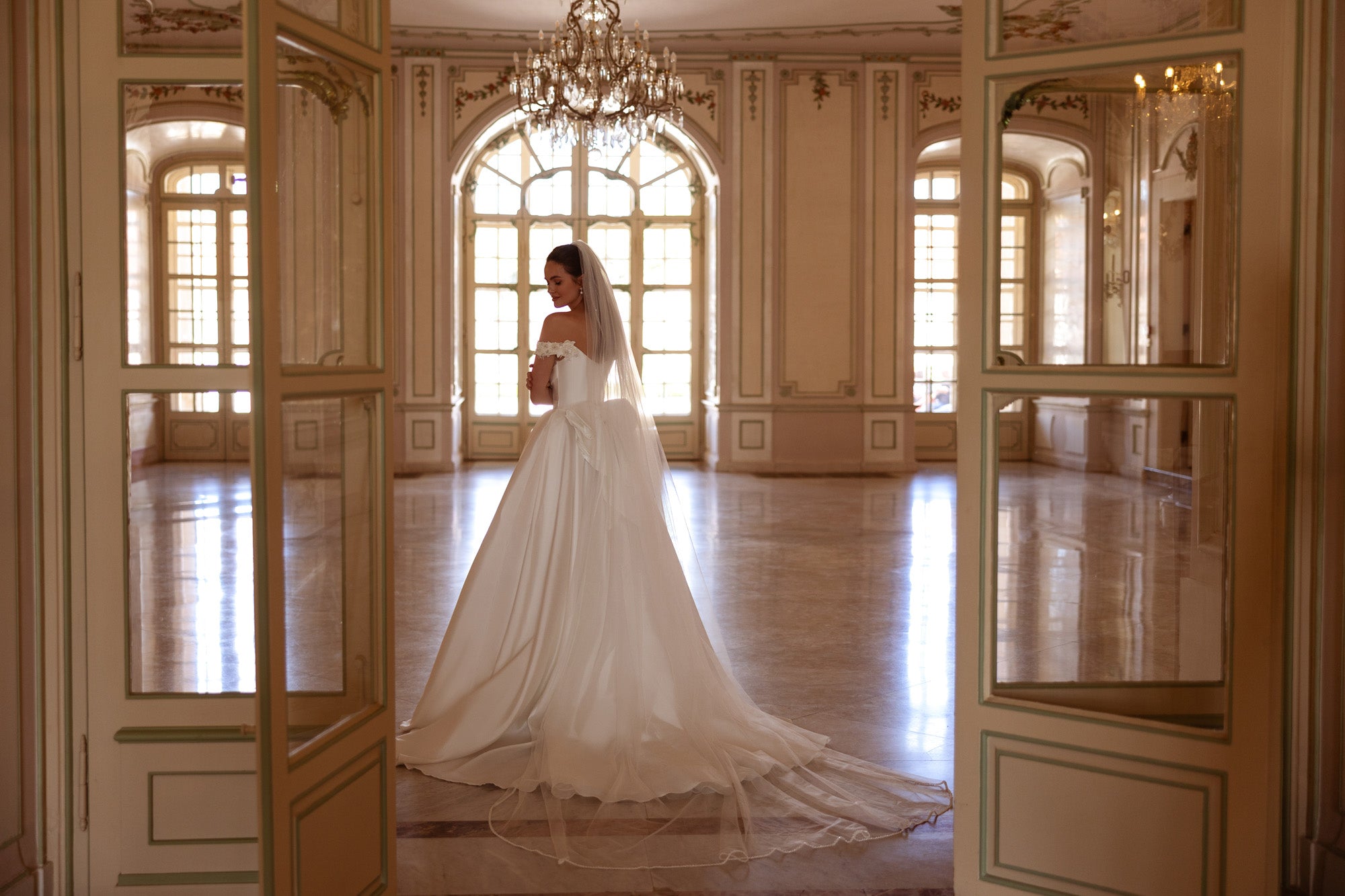 Ivory A-line wedding dress with an off-the-shoulder bodice and long flowing train
