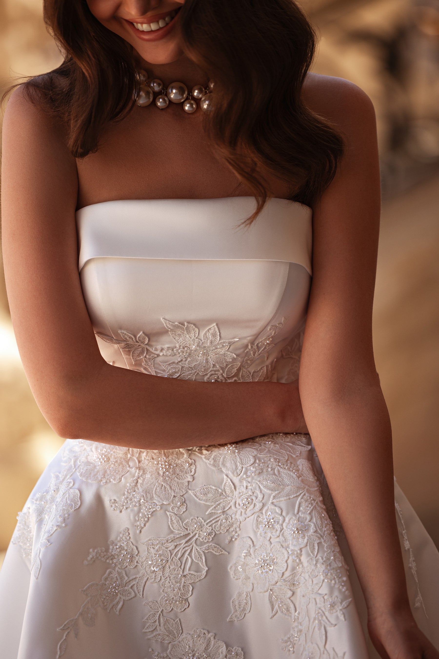 Ivory strapless wedding dress with a straight neckline and floral lace appliqués on the bodice and skirt
