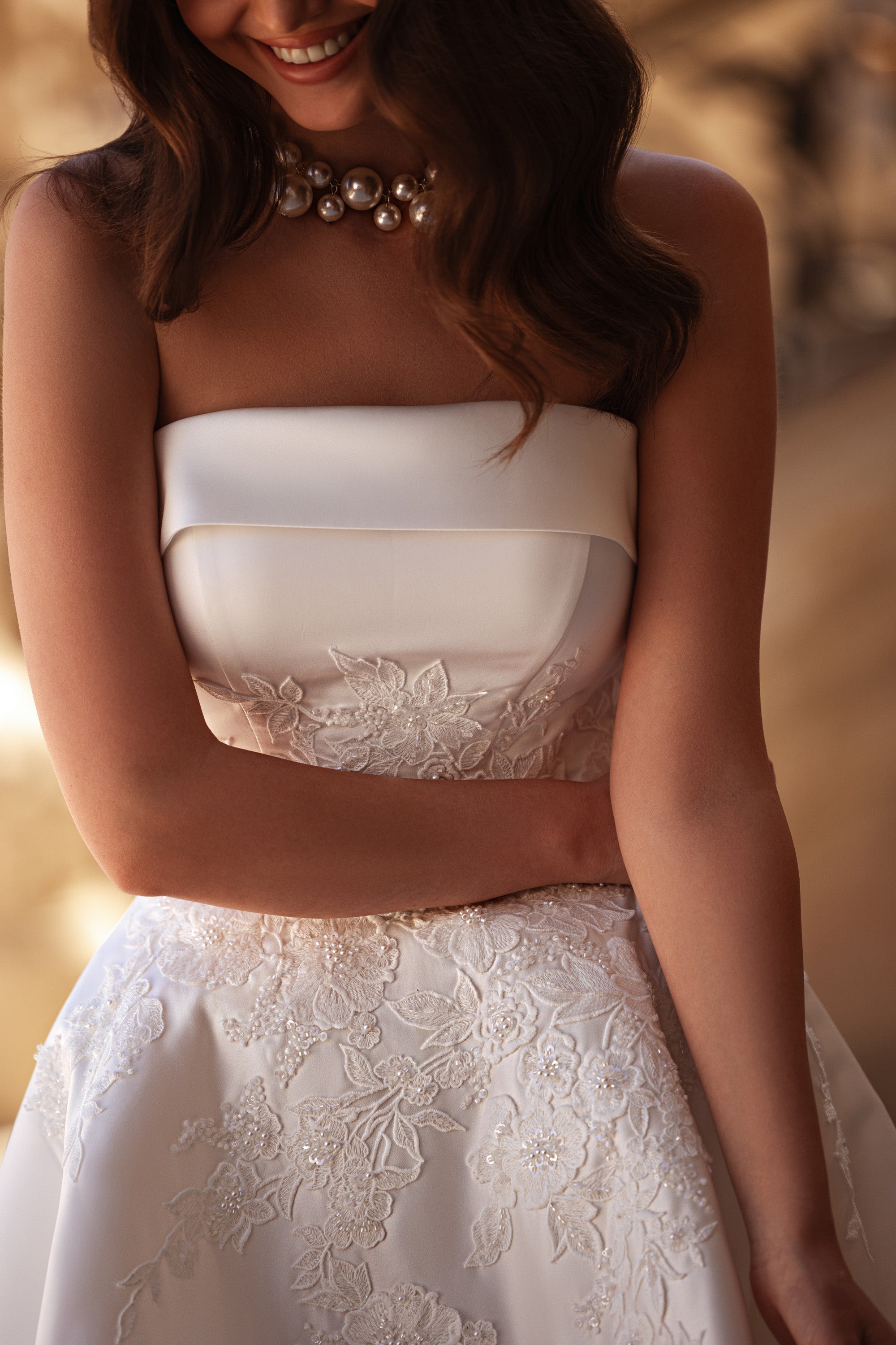 Ivory strapless wedding dress with a straight neckline and floral lace appliqués on the bodice and skirt