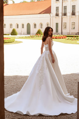 Back of an ivory A-line wedding dress with floral lace appliqués and a wide, sweeping train