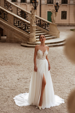 Ivory wedding dress featuring a lace V-neck bodice, draped skirt, high slit, and sweeping train