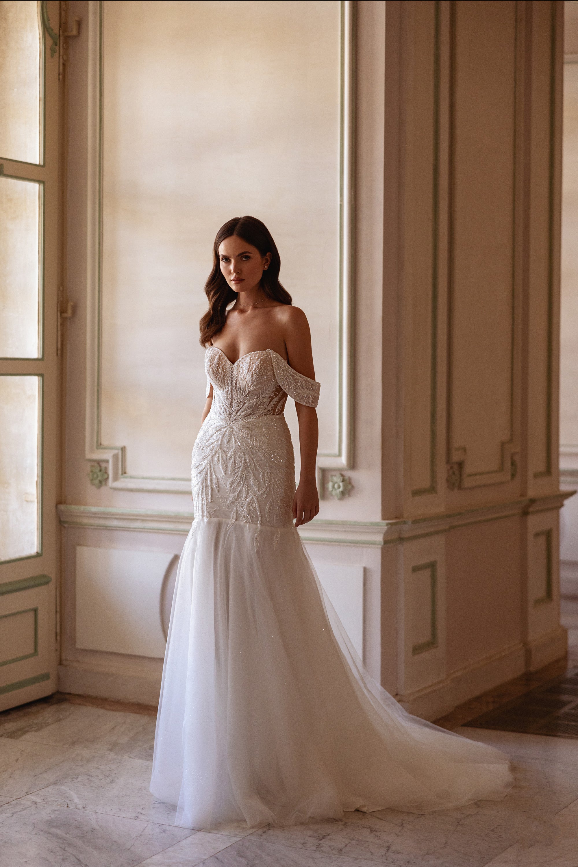 Full-length ivory mermaid wedding dress with off-the-shoulder sleeves, fitted lace bodice, and long train