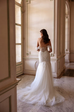 Ornate lace back and off-the-shoulder sleeves on an ivory mermaid wedding dress with a long train