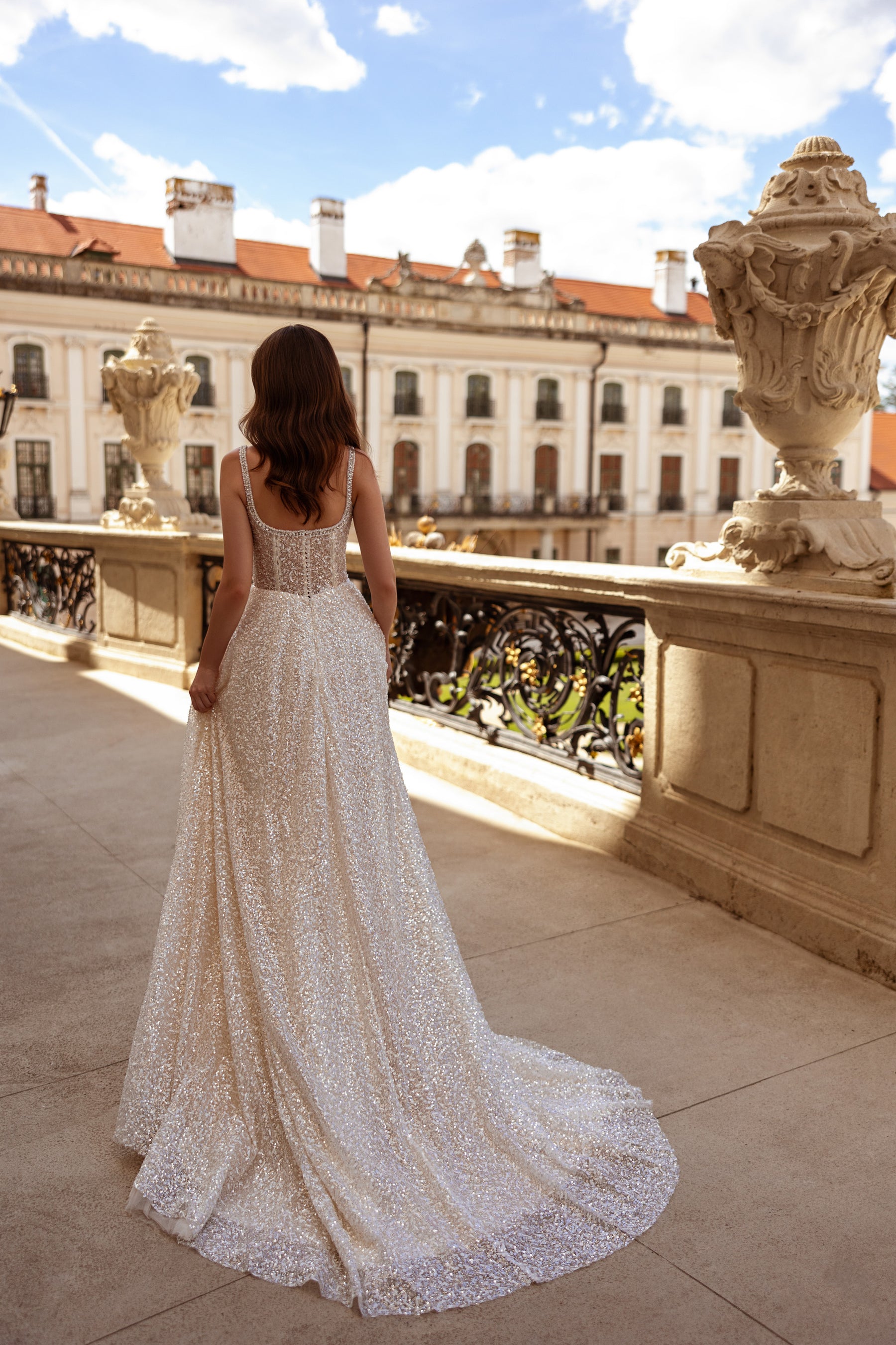 Low scoop back, slender beaded straps, and a sweeping train on a sparkling wedding dress