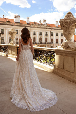 Low scoop back, slender beaded straps, and a sweeping train on a sparkling wedding dress