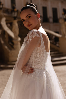 Ivory wedding dress with an open lace back, floral lace bodice, and sheer detachable cape