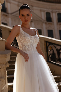 Close-up of an ivory wedding dress with a floral lace bodice, scoop neckline, and full tulle skirt