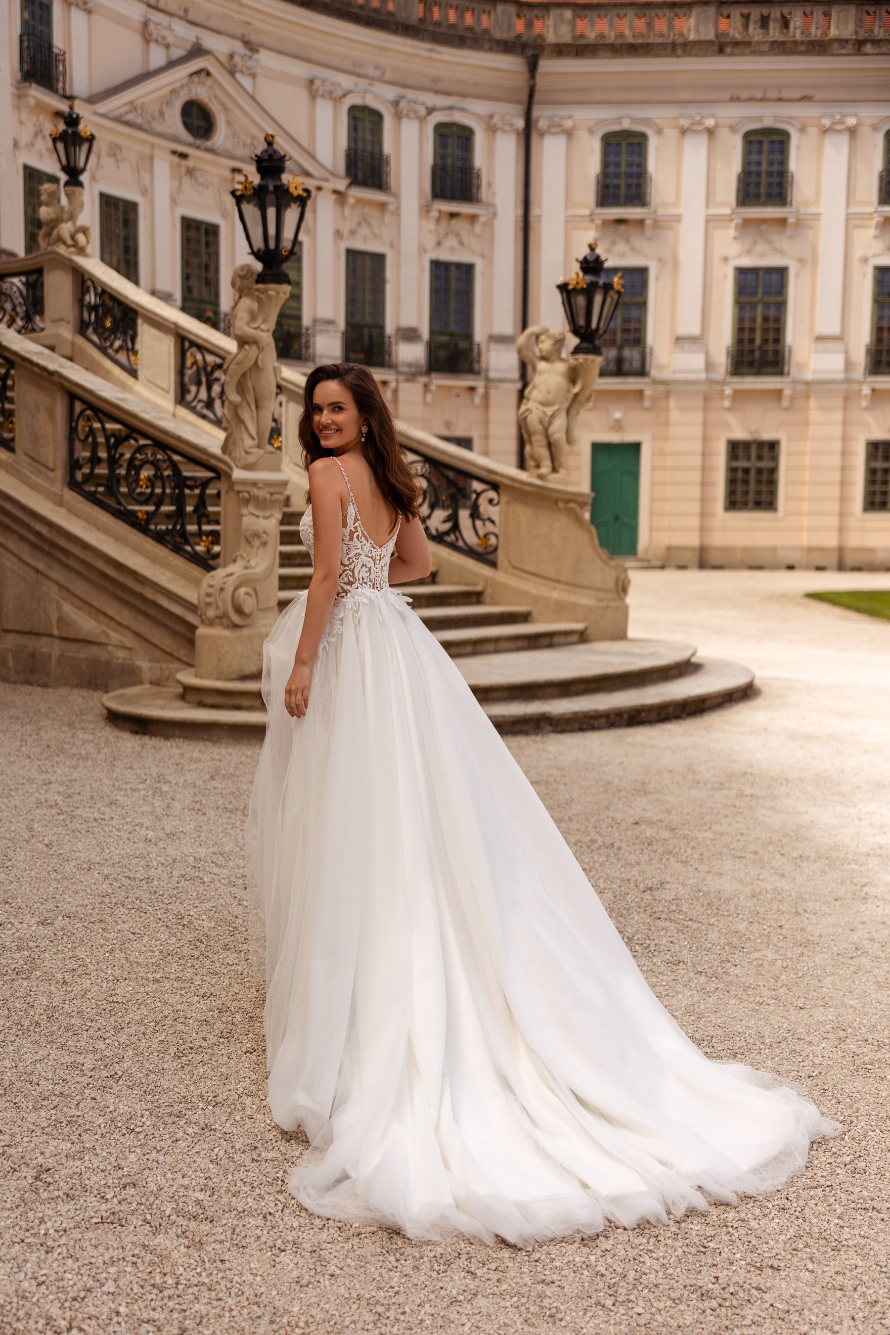 Ivory wedding dress with an open lace back, thin straps, and a long trailing train