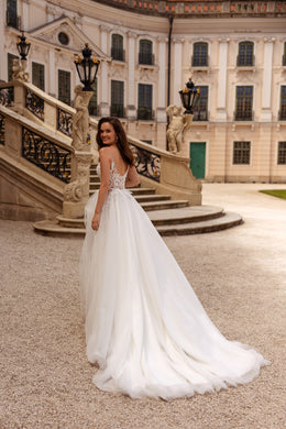 Ivory wedding dress with an open lace back, thin straps, and a long trailing train