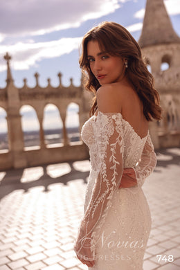 Three-quarter view of an ivory wedding dress showing sheer floral lace sleeves and a fitted mermaid silhouette