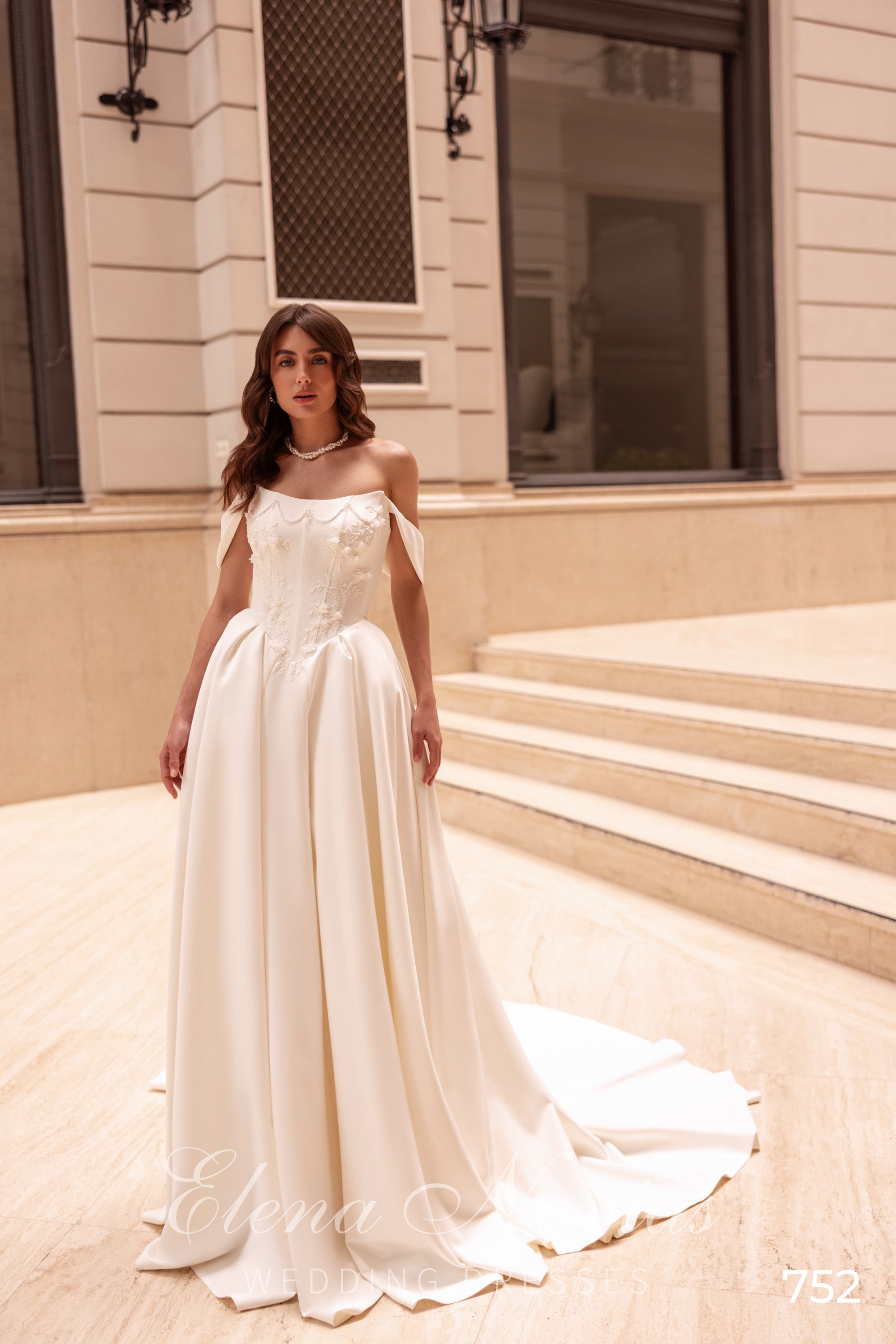 Ivory A-line wedding dress with floral bodice appliqués, off-the-shoulder straps, and a sweeping train