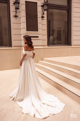 Long satin train flowing from the back of an ivory wedding dress with off-the-shoulder straps