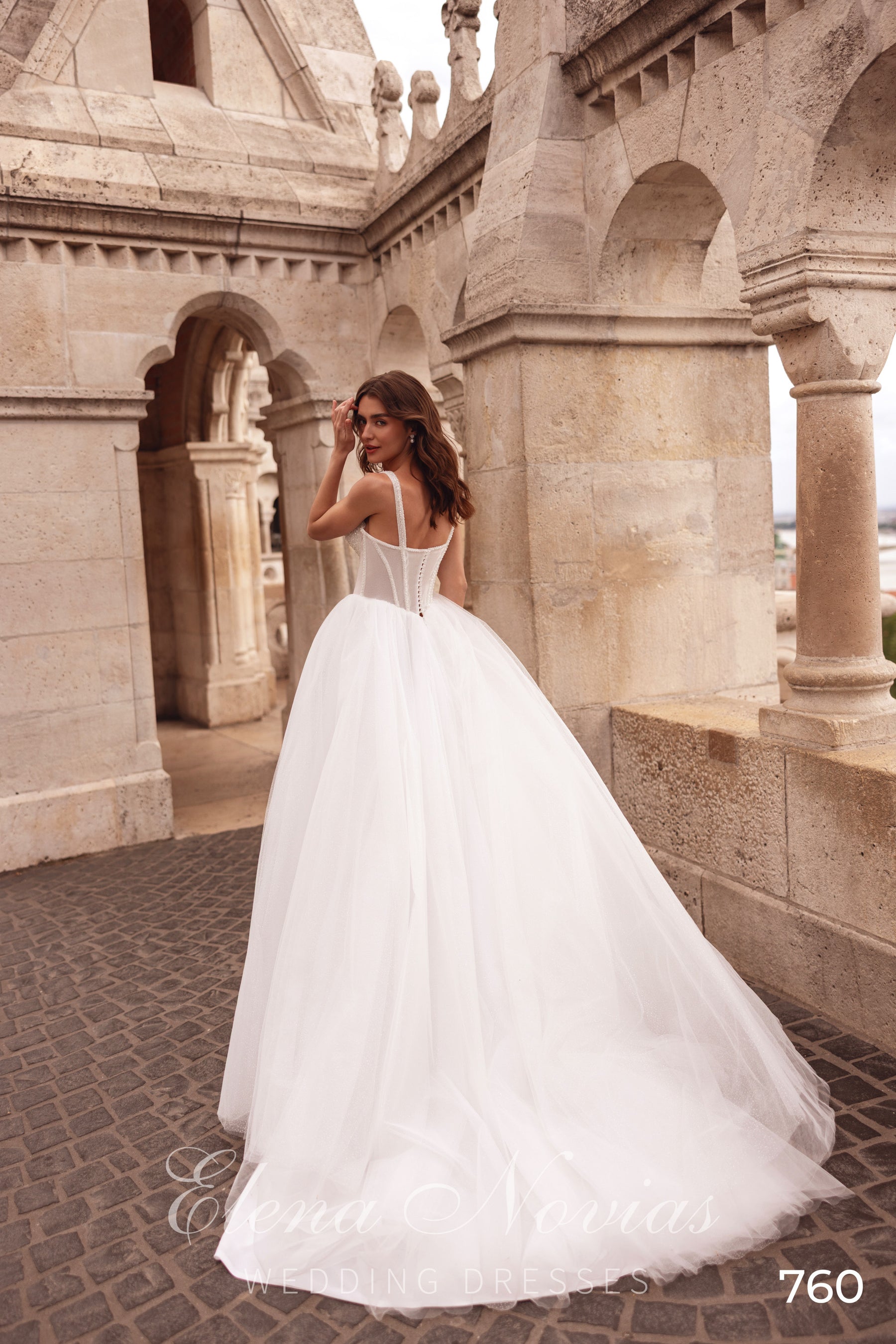 Low open-back ivory wedding dress with spaghetti straps, corset closure, and a full tulle train