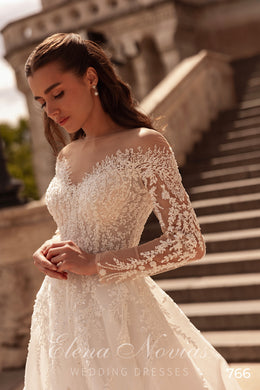 Ivory wedding dress with a sheer bateau neckline, long floral lace sleeves, and beaded lace bodice
