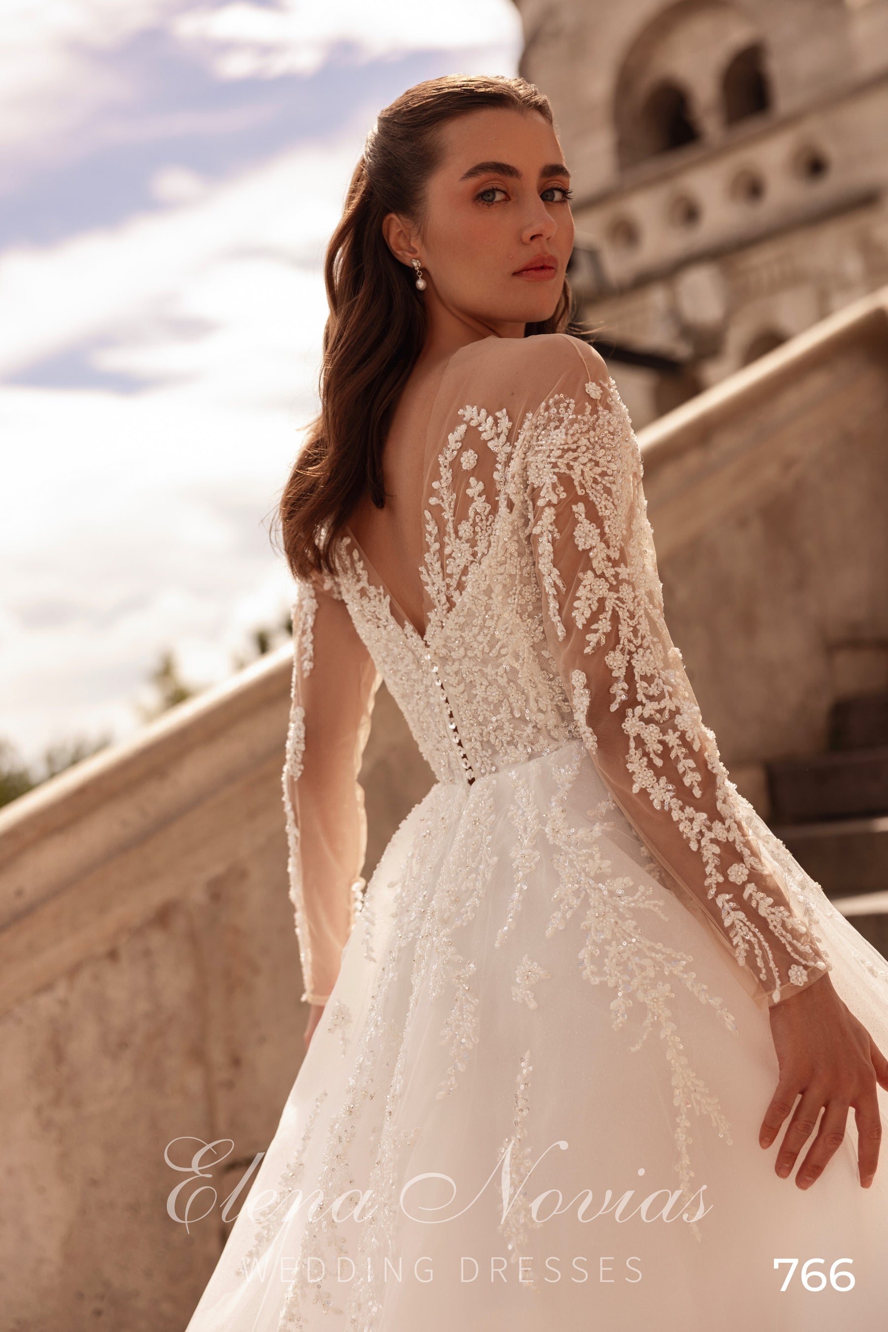 Open V-back ivory wedding dress with floral lace sleeves, beaded appliqués, and a full A-line skirt