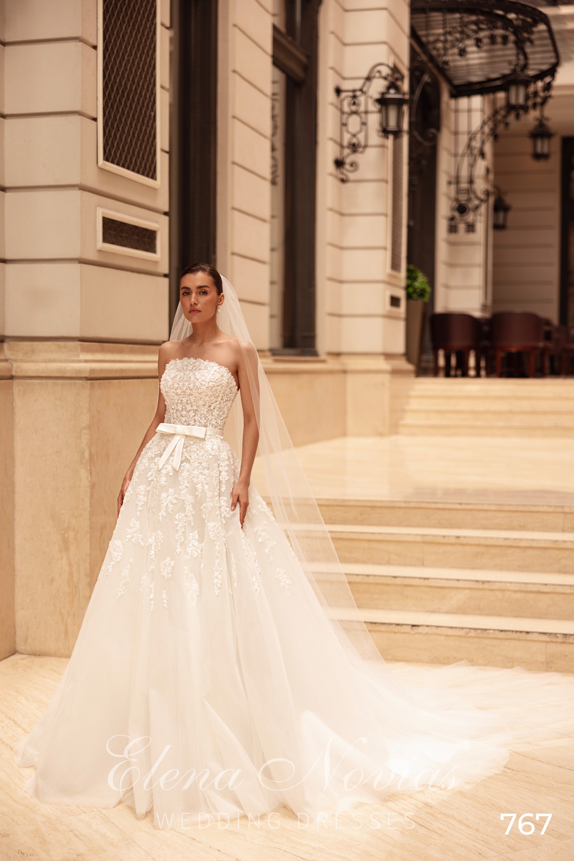Ivory A-line wedding dress with a strapless pearl-beaded bodice, bow belt, floral skirt, and long train