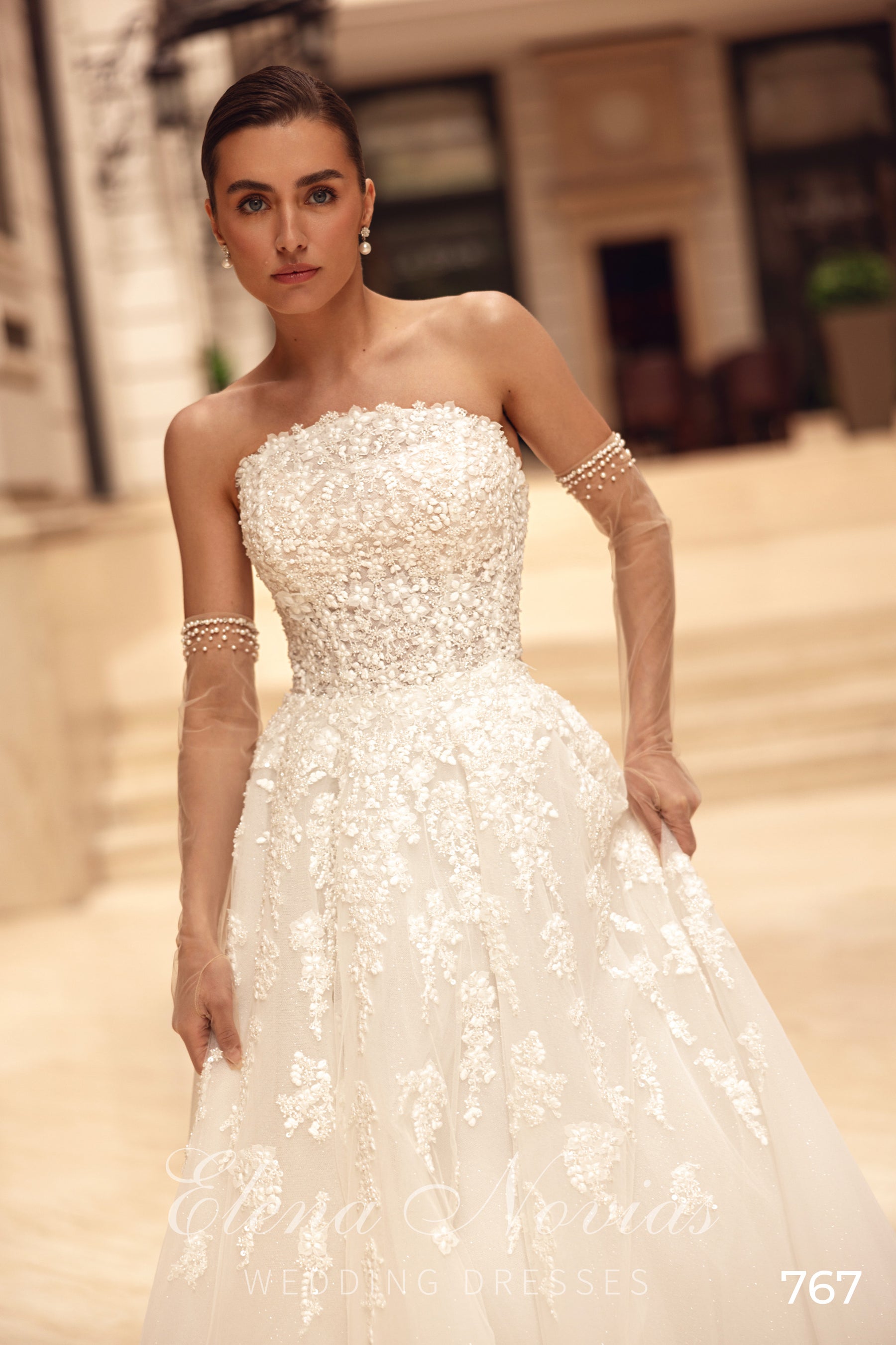 Strapless ivory wedding dress featuring a heavily beaded bodice, bow belt, and floral-patterned A-line skirt