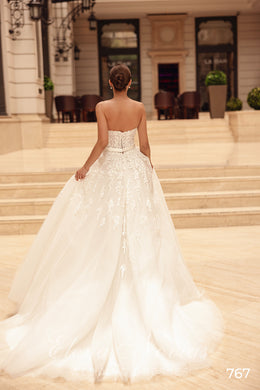 Strapless ivory wedding dress with a beaded back waist, flowing A-line skirt, and sweeping train