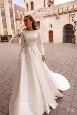Ivory A-line wedding dress with a bateau neckline, long sleeves, lace bodice, and sweeping train