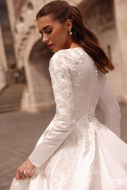Ivory wedding dress showing floral lace sleeves, a row of covered back buttons, and a satin A-line skirt