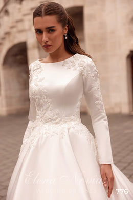 Ivory wedding dress with a high bateau neckline, long sleeves, floral lace appliqués, and an A-line skirt