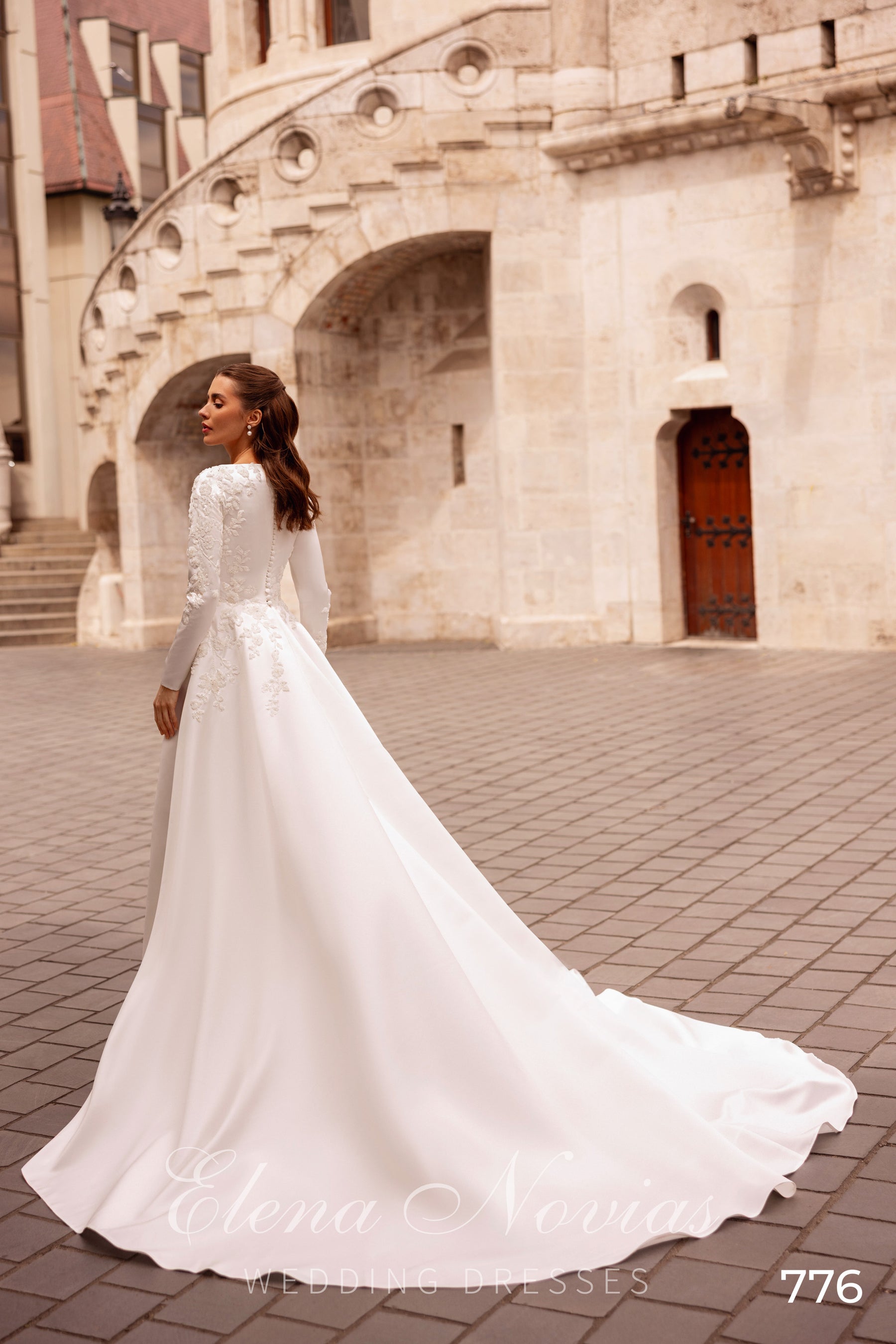 Rear view of an ivory wedding dress with lace-covered back details and a long flowing train