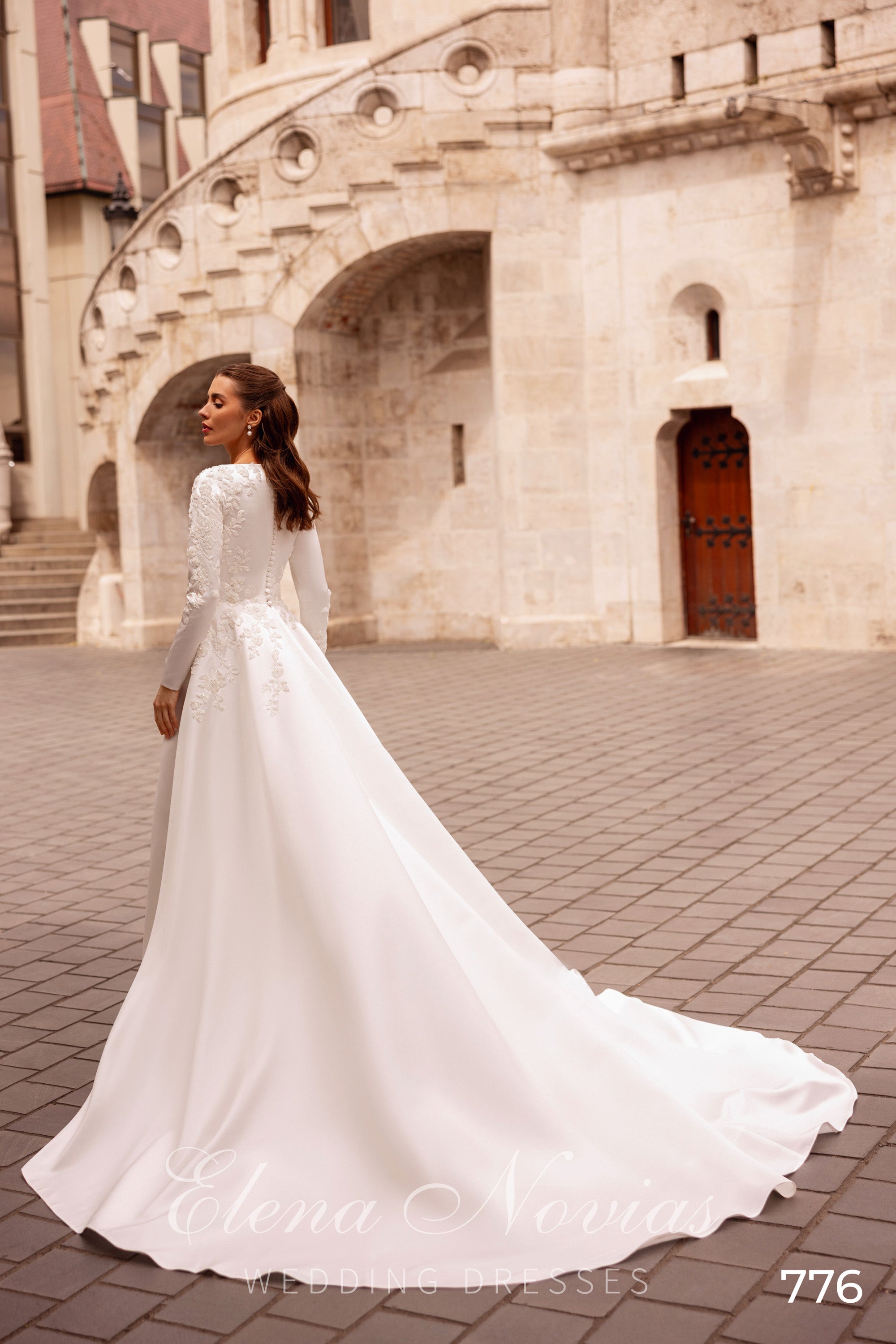 Rear view of an ivory wedding dress with lace-covered back details and a long flowing train