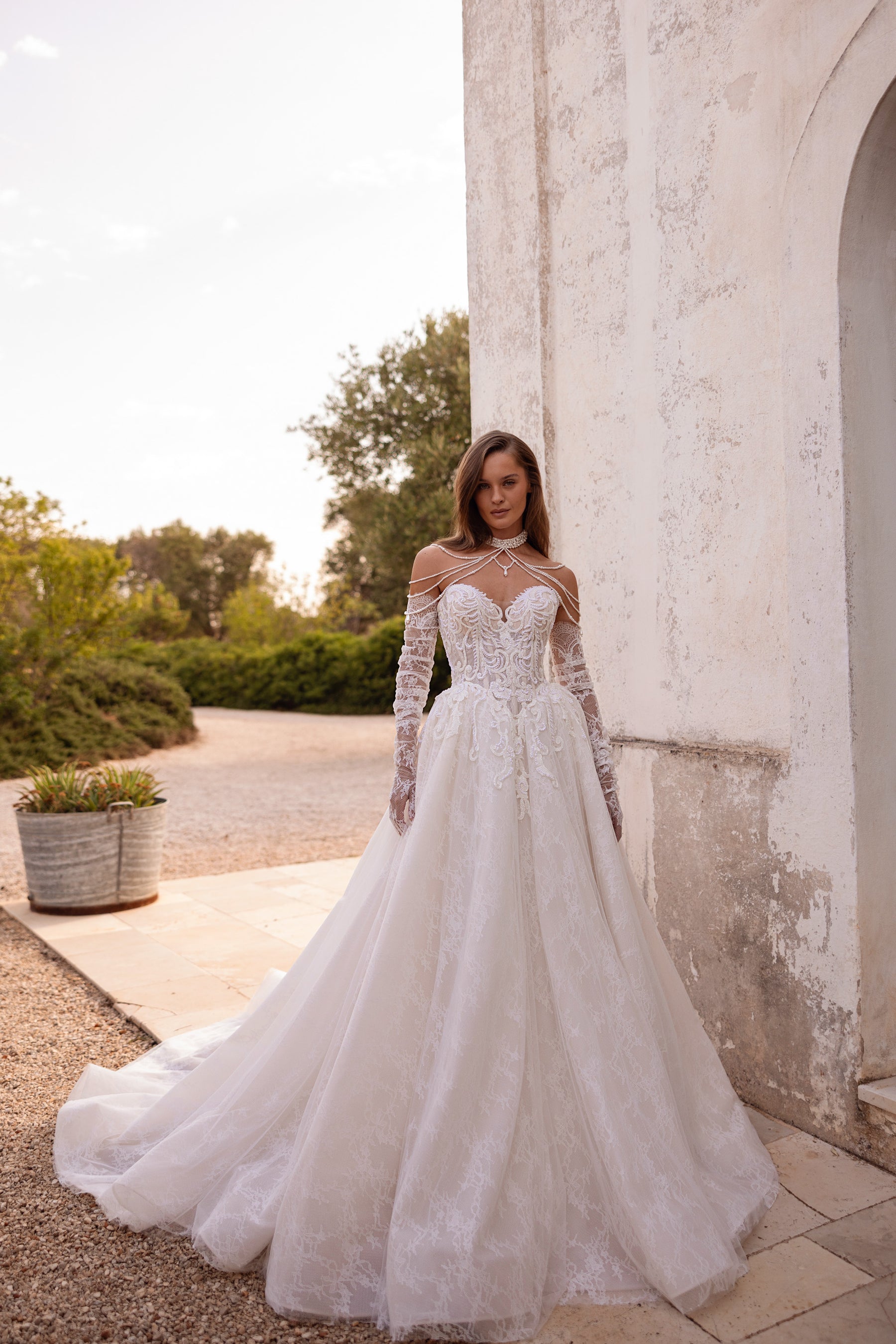 Ivory ball gown wedding dress with floral lace sleeves, beaded illusion neckline, and a sweeping train