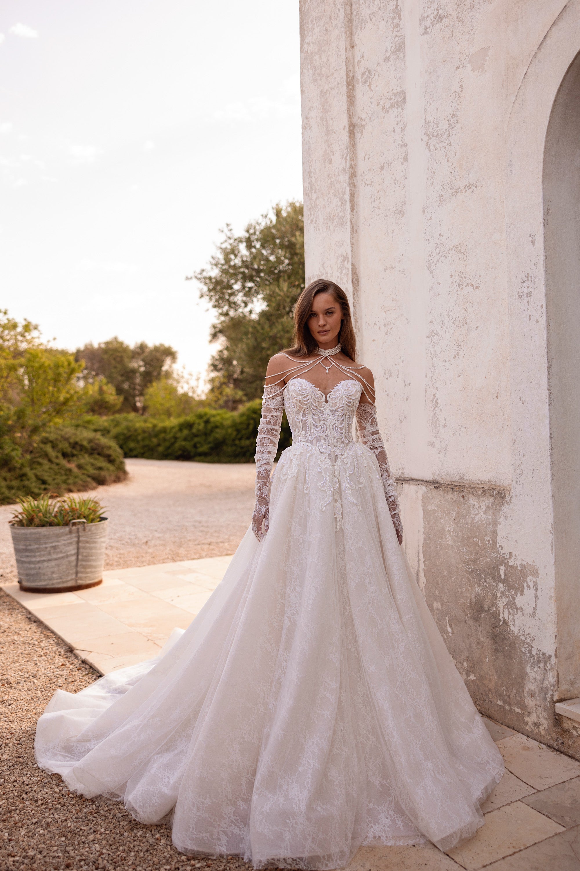 Ivory ball gown wedding dress with floral lace sleeves, beaded illusion neckline, and a sweeping train